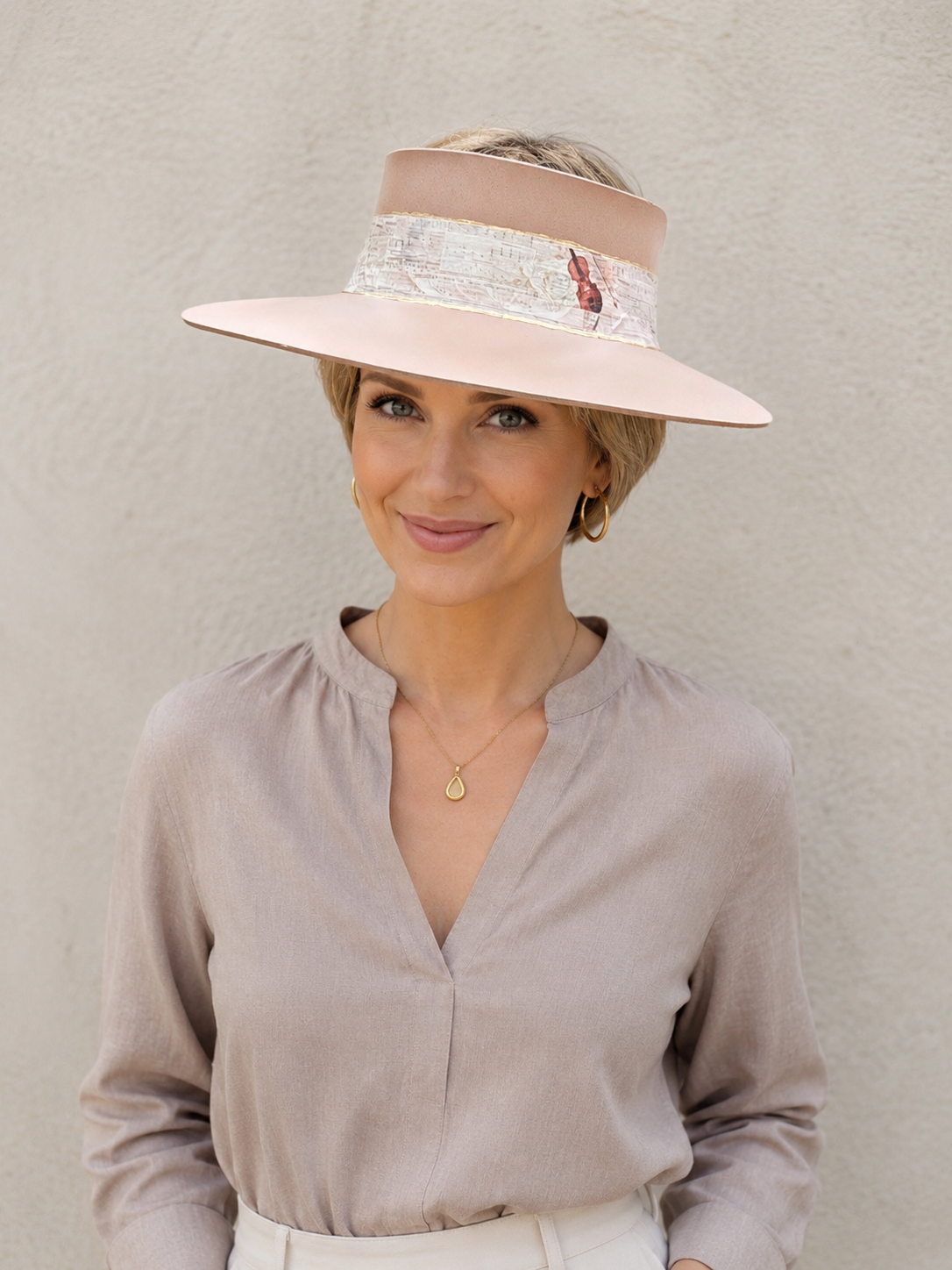 Woman wearing a wide-brimmed hat with a decorative band against a plain background