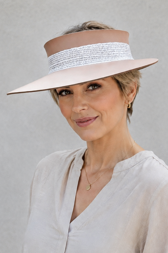 Woman wearing a beige visor hat and light-colored shirt against a plain background