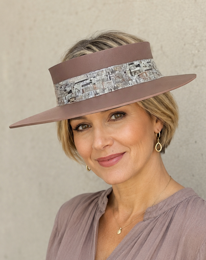 Woman wearing a brown hat with a decorative band against a plain background