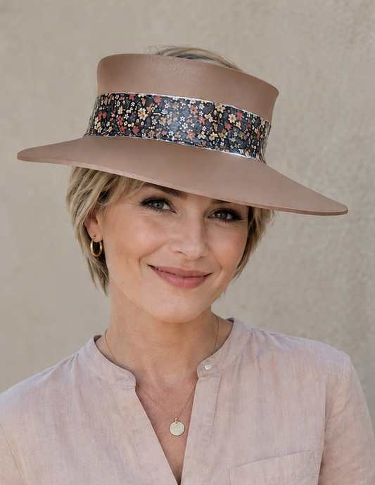 Woman wearing a beige hat with a floral band against a plain background