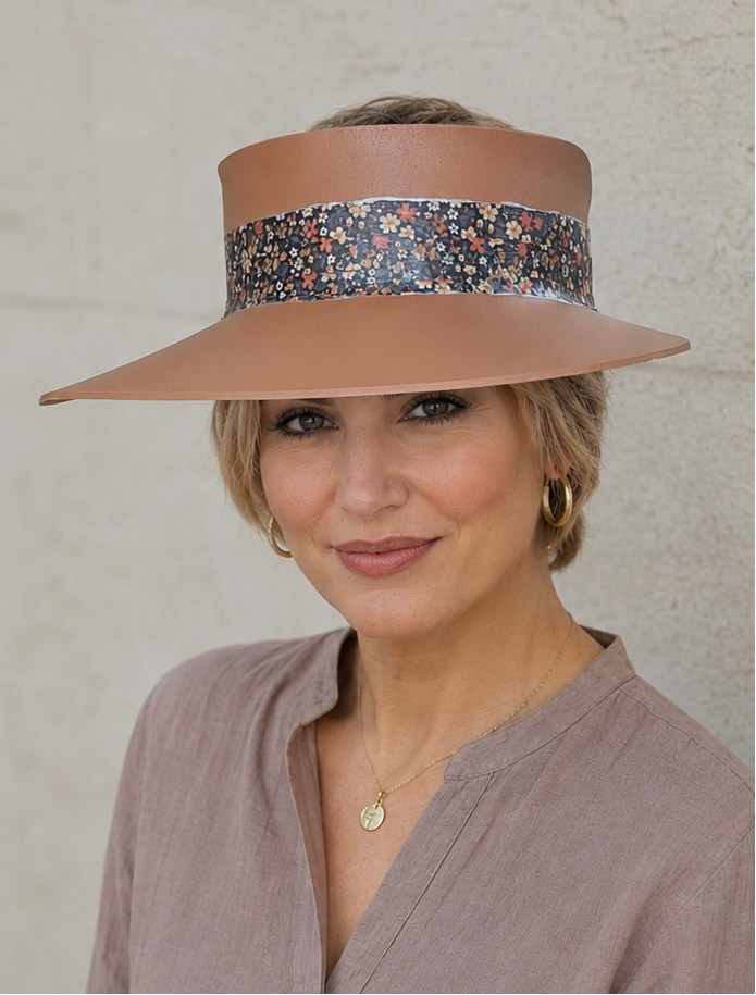 Woman wearing a wide-brimmed hat with a floral band against a neutral background