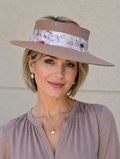Woman wearing a wide-brimmed hat with floral band against a beige wall