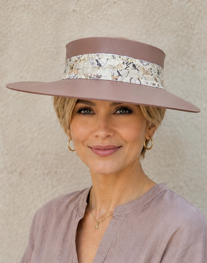 Woman wearing a wide-brimmed hat with a floral band against a beige background