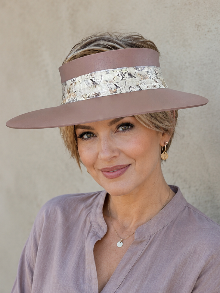 Woman wearing a wide-brimmed hat with a decorative band against a neutral background