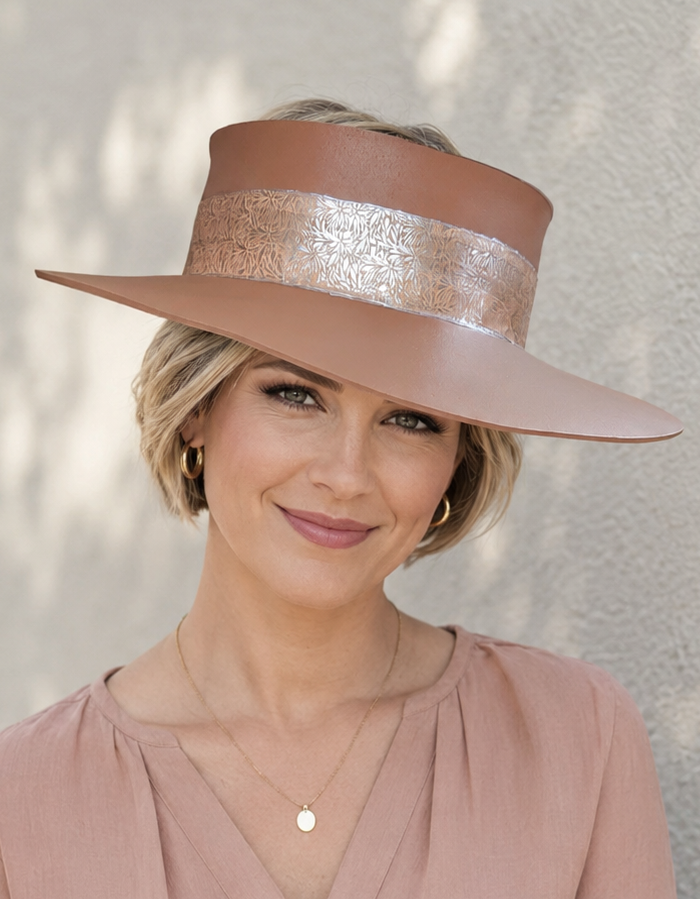 Woman wearing a wide-brimmed hat with a metallic band against a light background