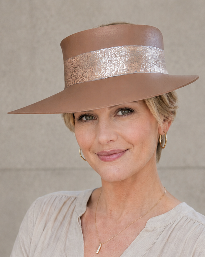 Woman wearing a beige hat with a decorative band against a plain background