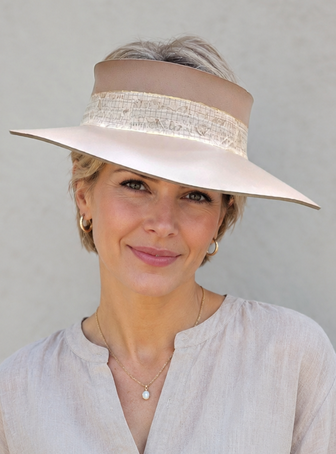 Woman wearing a beige hat with a wide brim against a plain background