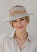Woman wearing a beige visor hat with a floral band against a plain background