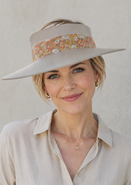Woman wearing a beige visor hat with a floral band against a plain background