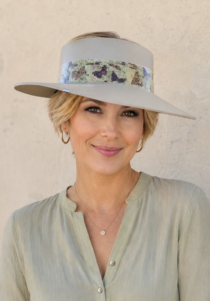 Woman wearing a wide-brimmed hat with floral band against a beige wall
