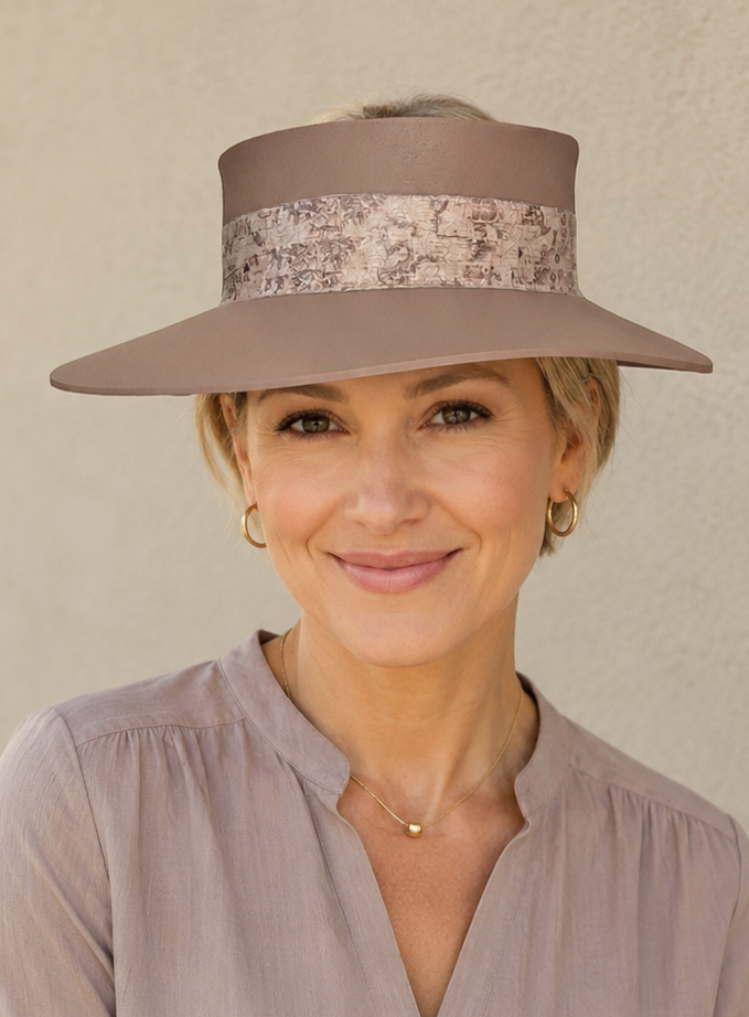 Woman wearing a beige hat and light purple blouse against a plain background