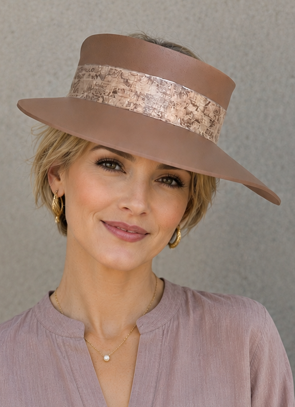 Woman wearing a brown hat and a light pink blouse against a gray background