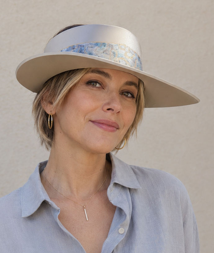Woman wearing a light blue shirt and beige hat against a plain background