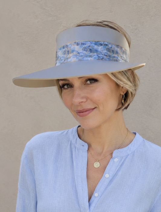 Woman wearing a light blue visor and matching shirt against a beige background