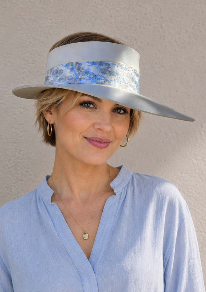 Woman wearing a light blue visor hat against a plain background
