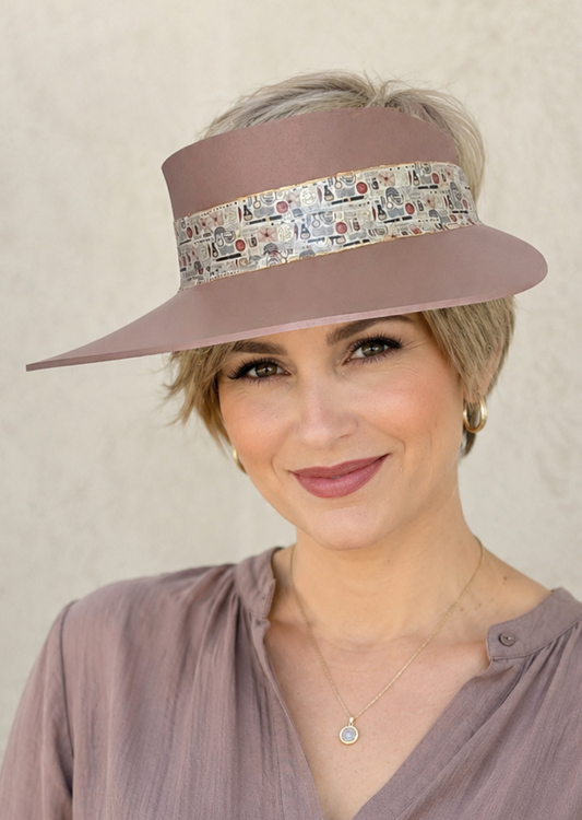Woman wearing a brown visor hat with a patterned band against a beige background