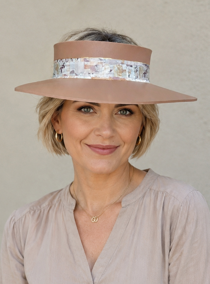 Woman wearing a wide-brimmed hat with a decorative band against a neutral background