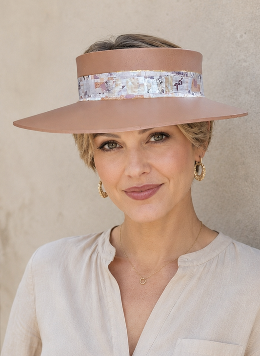 Woman wearing a wide-brimmed hat with a floral band against a beige wall