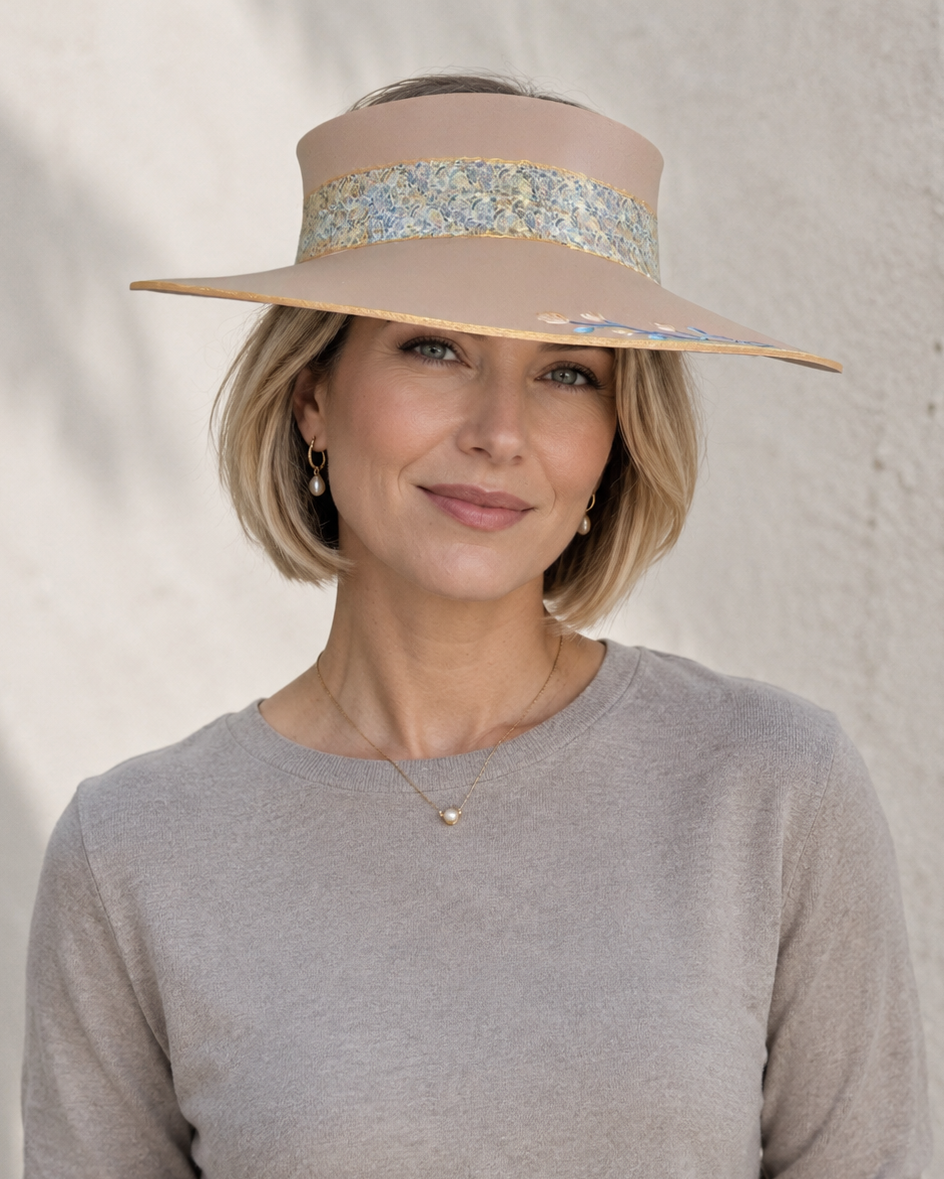 Woman wearing a wide-brimmed hat with a floral band against a neutral background