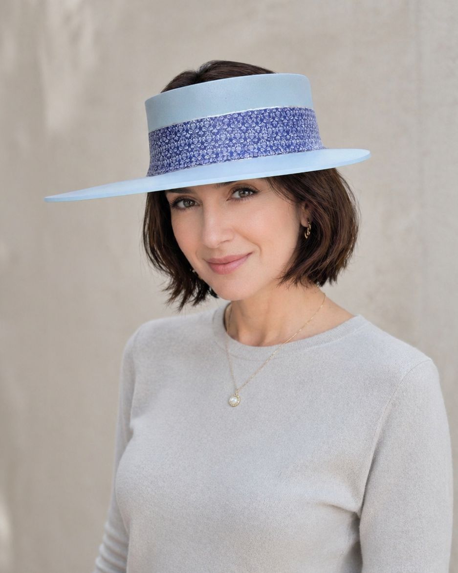 Woman wearing a light blue sun hat with a decorative band on a neutral background