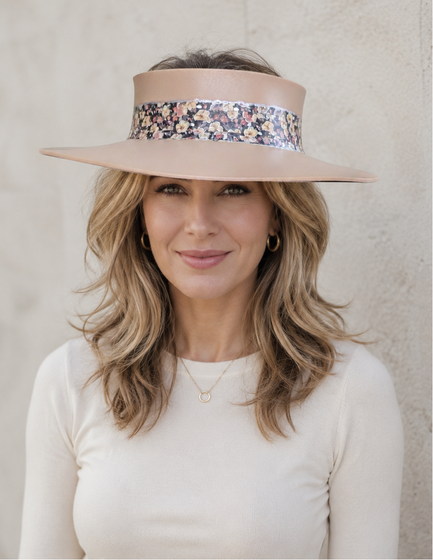 Woman wearing a beige visor with floral band against a plain background