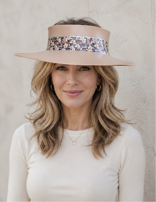 Woman wearing a beige visor with floral band against a plain background