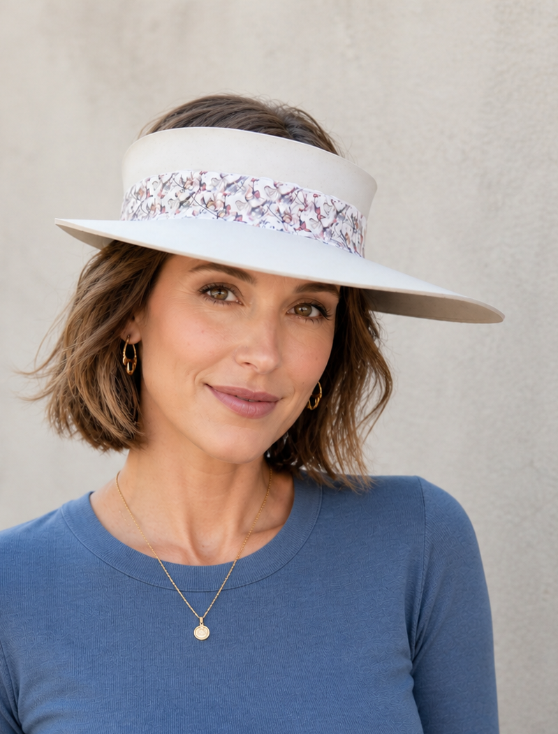 Woman wearing a white visor with floral band against a plain background