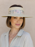 Woman wearing a light-colored visor with floral pattern against a beige background
