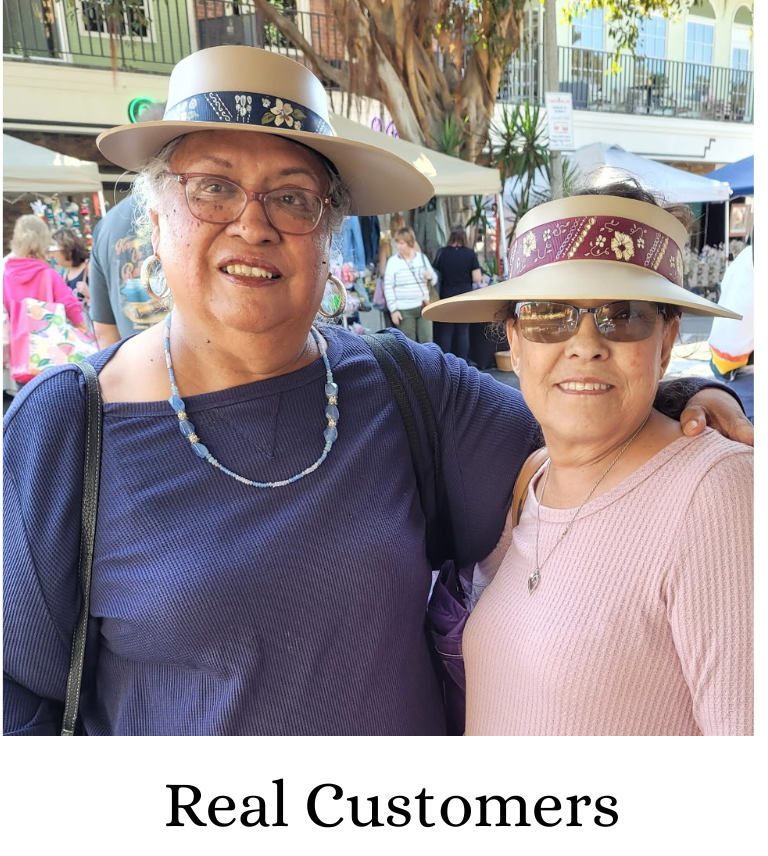 A white card or print featuring a square color photograph of two smiling women outdoors wearing wide-brim sun hats, with the text 'Real Customers' printed below.