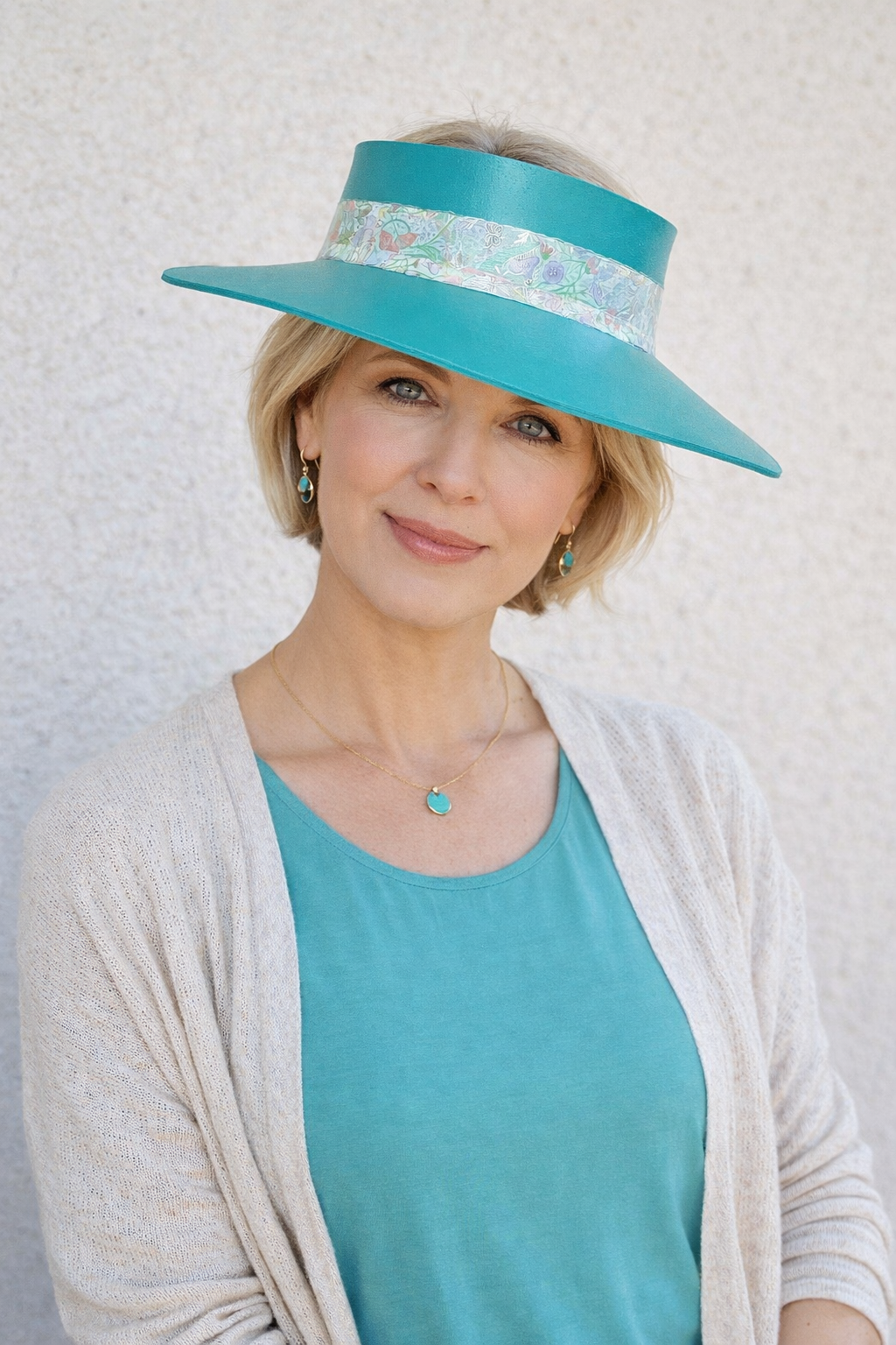 Woman wearing a turquoise hat with a white band against a light background