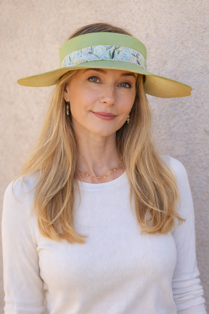 Woman wearing a green visor with floral pattern against a beige wall