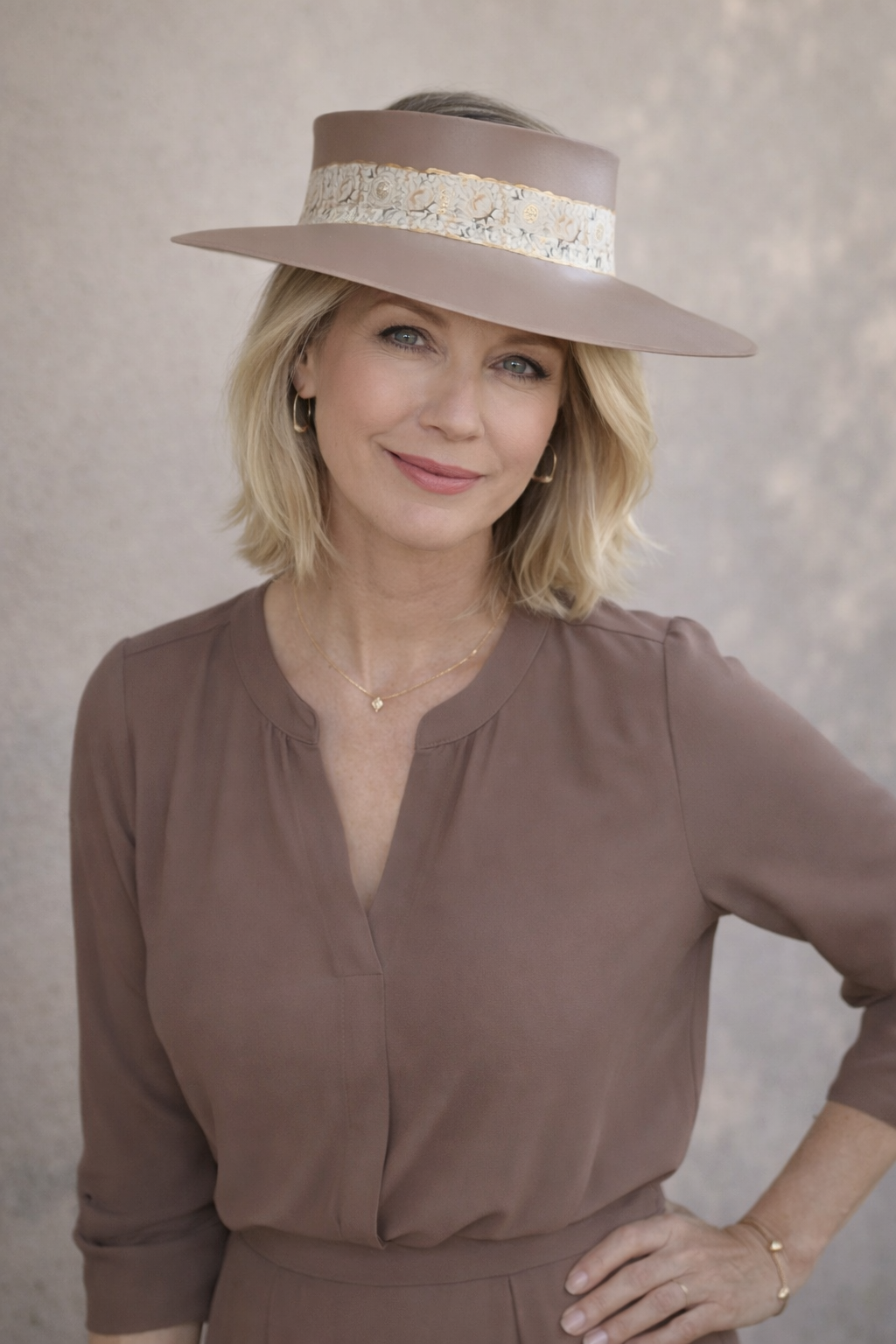 Woman wearing a brown hat and matching blouse against a neutral background