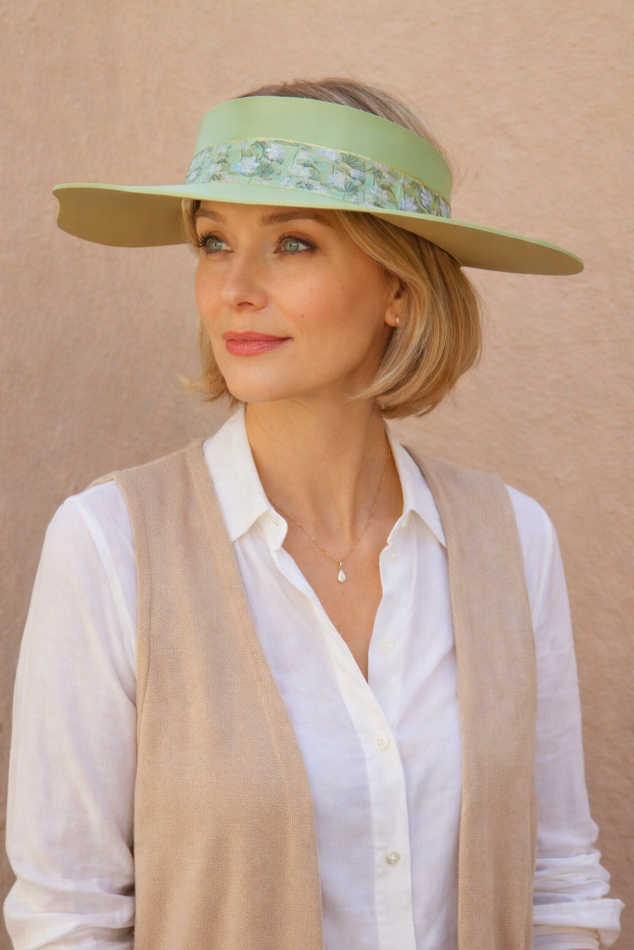 Woman wearing a green visor hat with floral band against a beige background