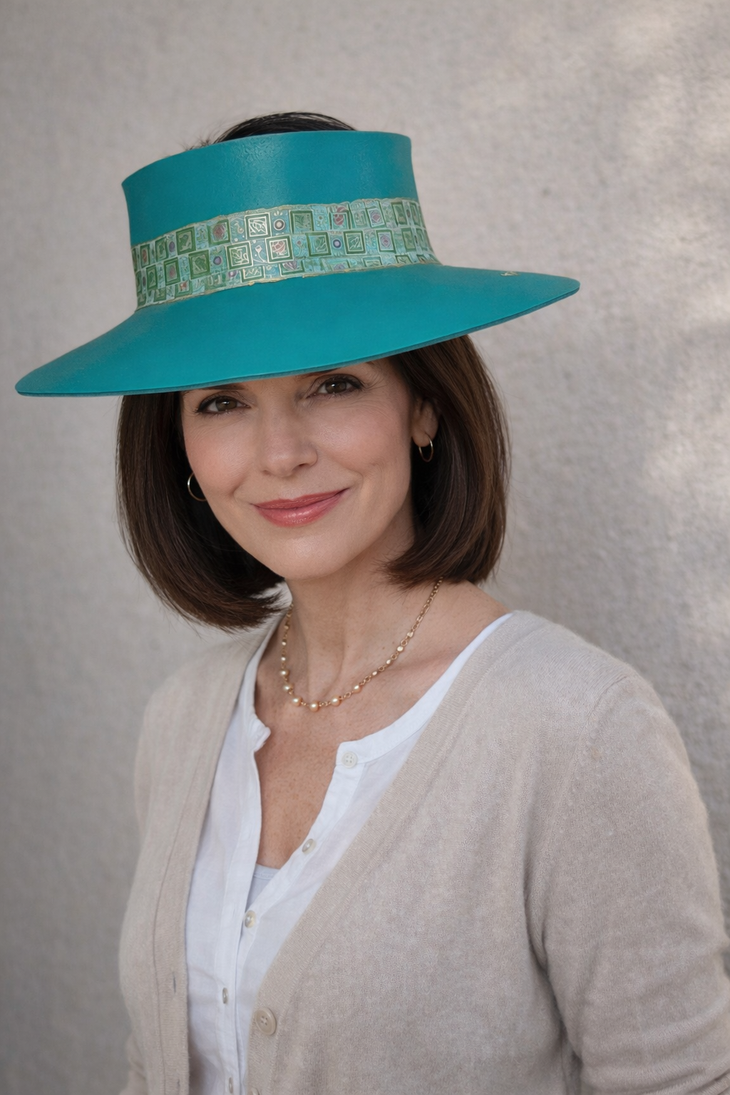 Woman wearing a turquoise hat with a patterned band against a neutral background