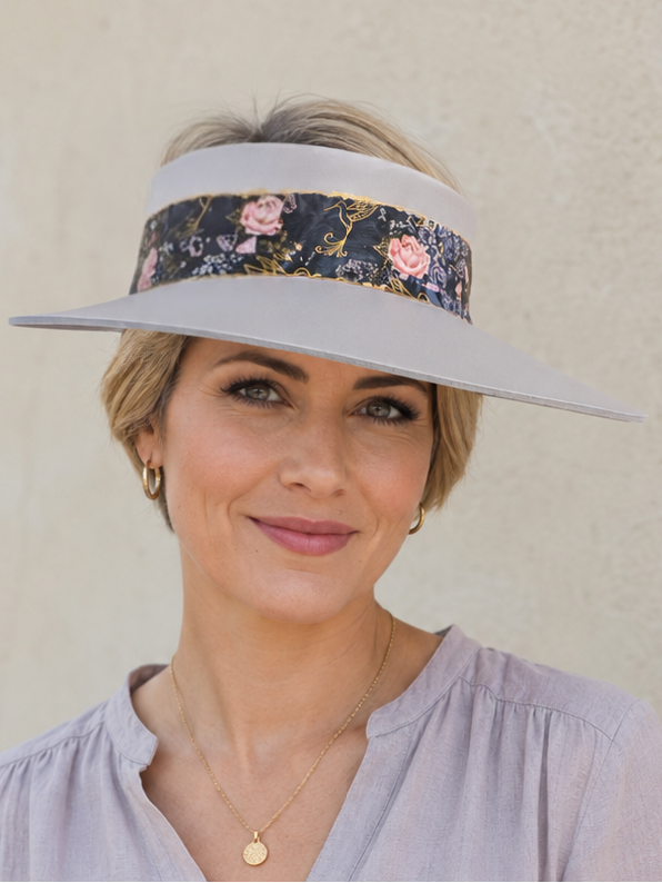 Woman wearing a light purple shirt and a floral visor against a beige wall