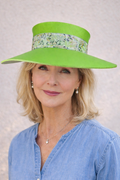 Woman wearing a bright green hat with a floral band against a neutral background