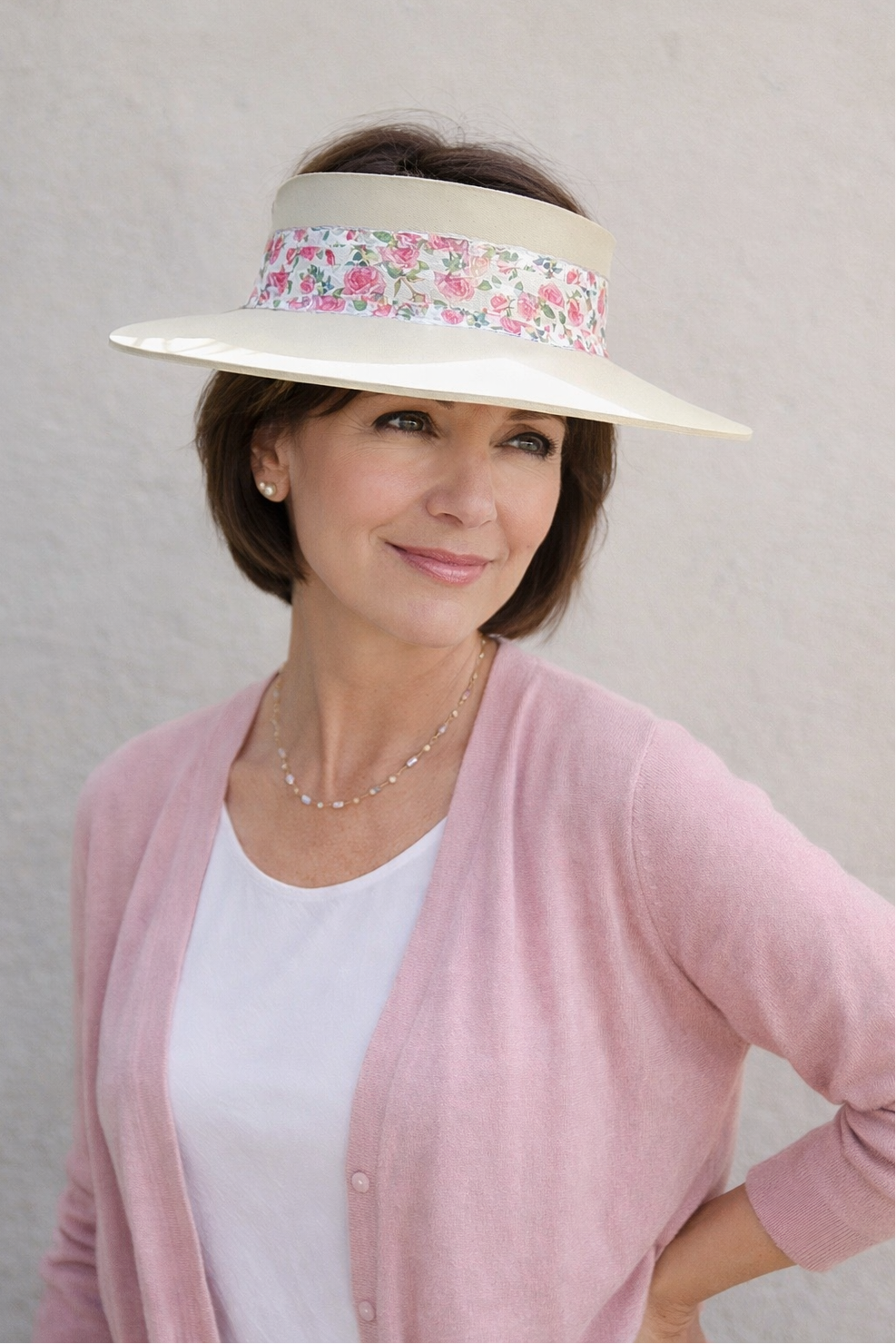 Woman wearing a white visor with floral band against a plain background
