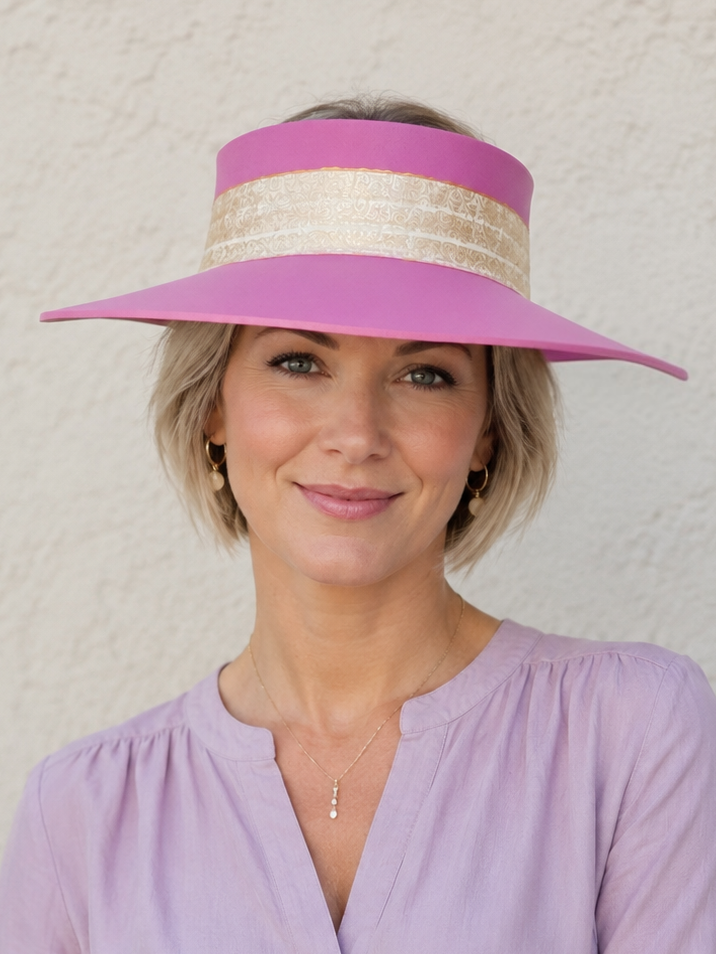 Woman wearing a pink visor and light purple blouse against a white background