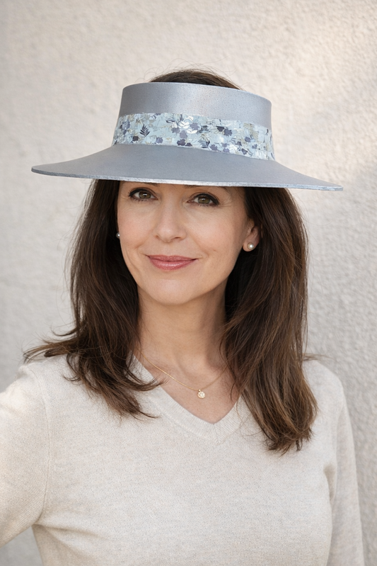 Woman wearing a wide-brimmed hat with floral details against a plain background