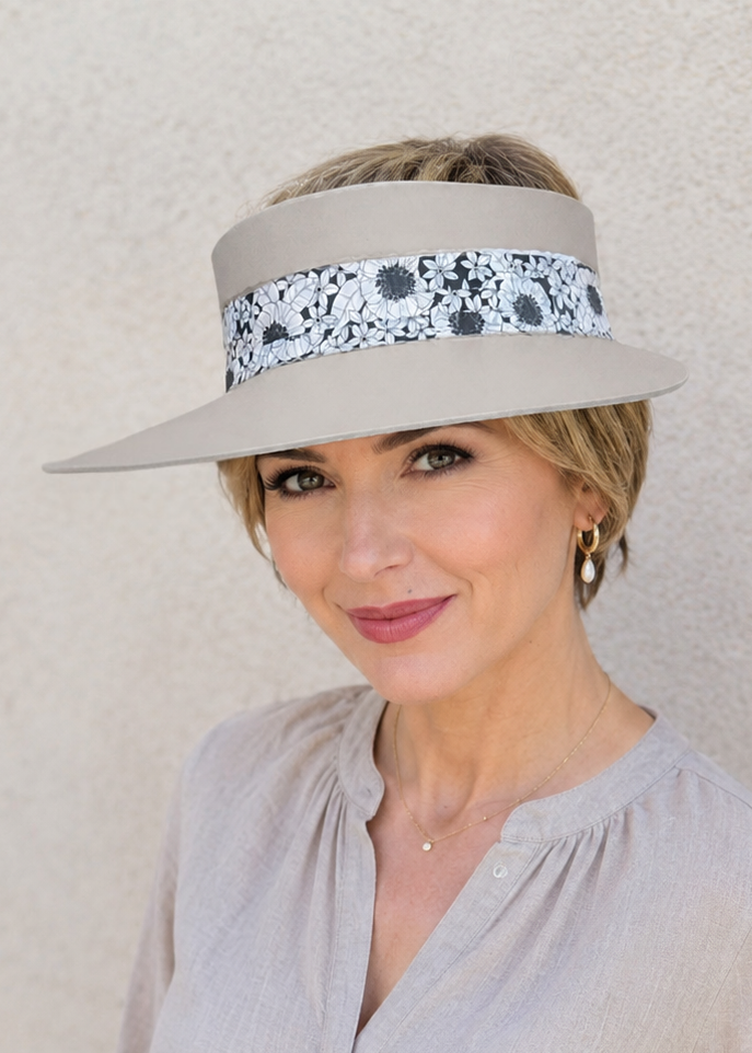 Woman wearing a beige visor with floral band against a plain background