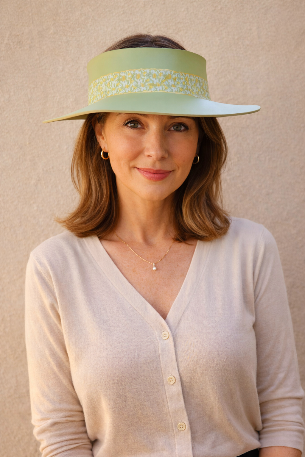 Woman wearing a light green visor hat against a beige background