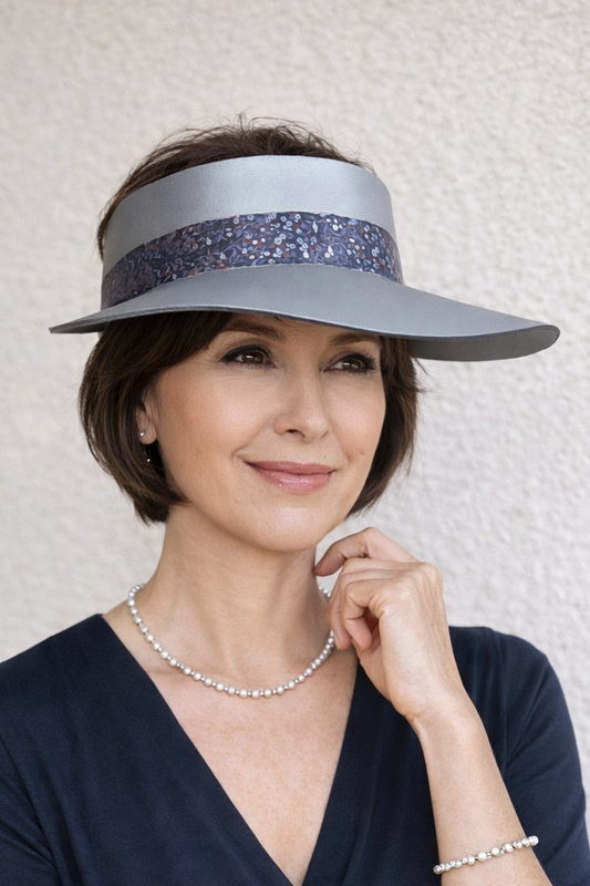 Woman wearing a wide-brimmed hat with a decorative band against a neutral background