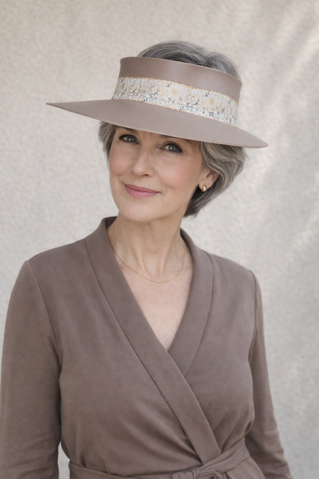 Woman wearing a brown hat with decorative band against a neutral background