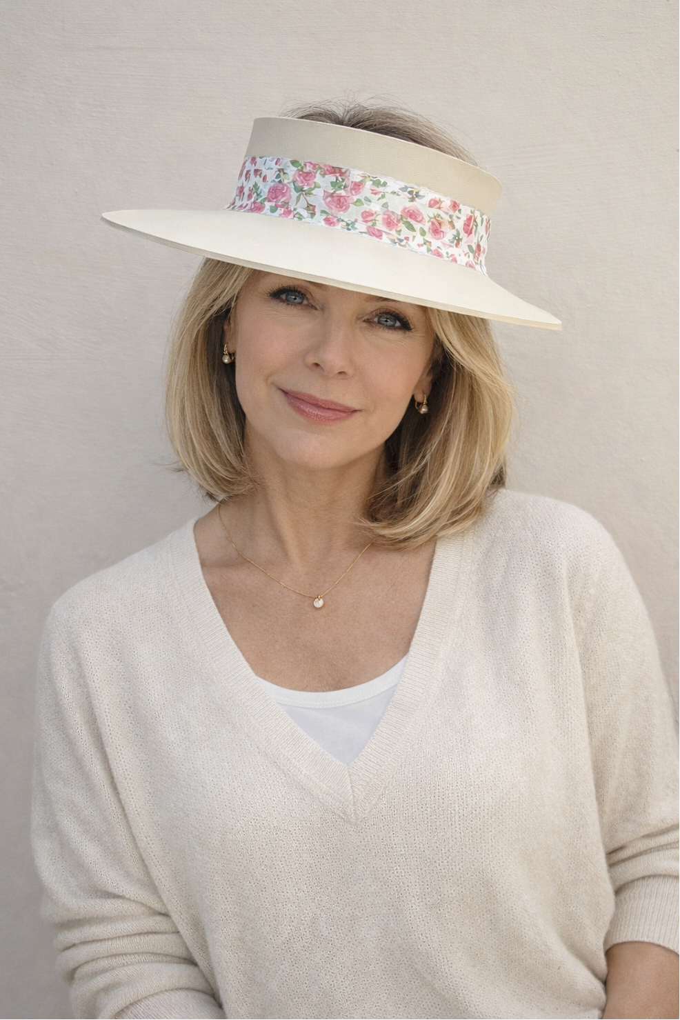 Woman wearing a wide-brimmed hat with floral band against a plain background