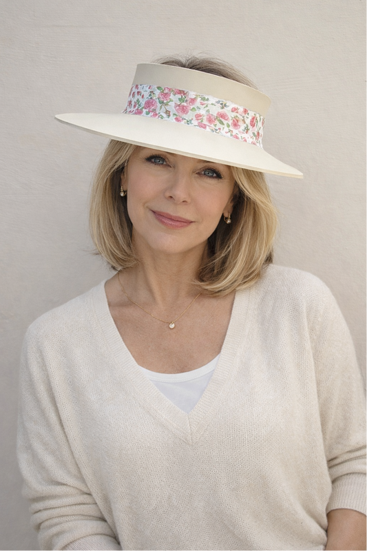 Woman wearing a wide-brimmed hat with floral band against a plain background