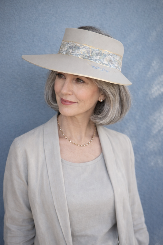 Woman wearing a wide-brimmed hat with a decorative band against a blue background