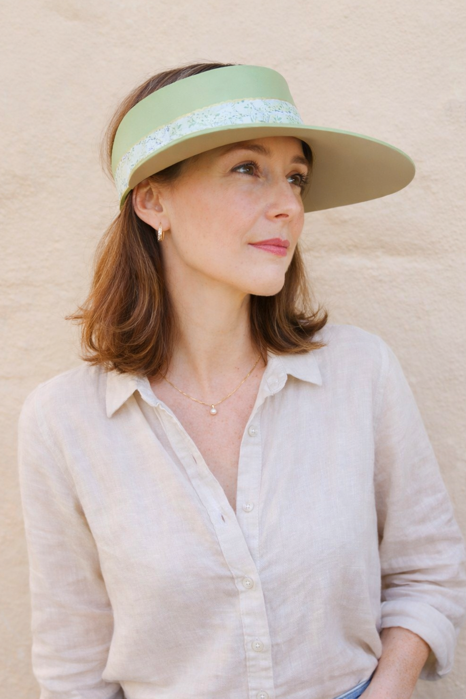 Woman wearing a light-colored visor against a beige background