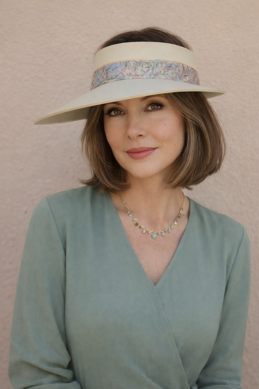 Woman wearing a wide-brimmed hat with a floral band against a beige background