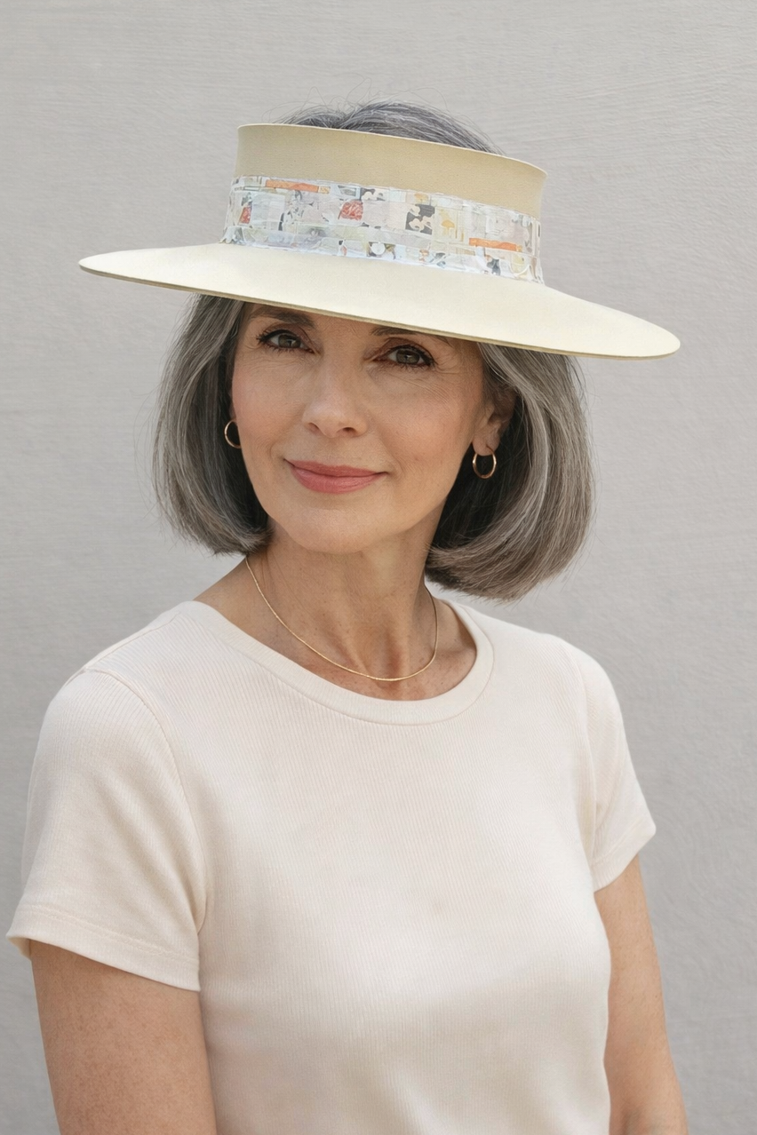 Woman wearing a wide-brimmed hat with floral band against a gray background