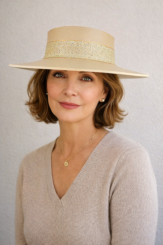 Woman wearing a beige hat with a gold band against a plain background